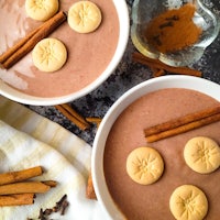 two bowls of chocolate pudding with cinnamon and cinnamon sticks