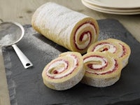 a slice of raspberry roll with powdered sugar and a spoon