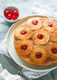 a pineapple upside down cake on a plate with cherries