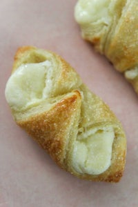 two crescent rolls with cheese and bananas on a pink plate