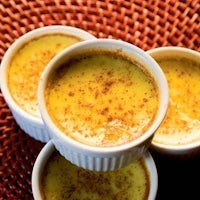 three bowls of yellow pudding on a table